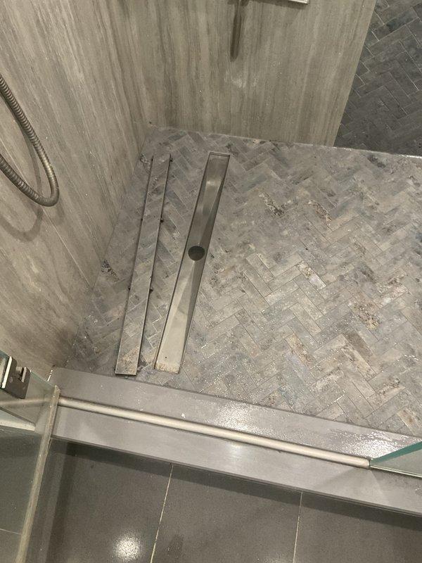 Responded to service call for drain maintenance requiring two-person crew with ladder access. Upon arrival, accessed and cleared the drain system in the modern bathroom featuring herringbone-tiled shower with linear center drain. Successfully completed drain servicing work, ensuring proper water flow and drainage function throughout the shower and bathroom plumbing system.