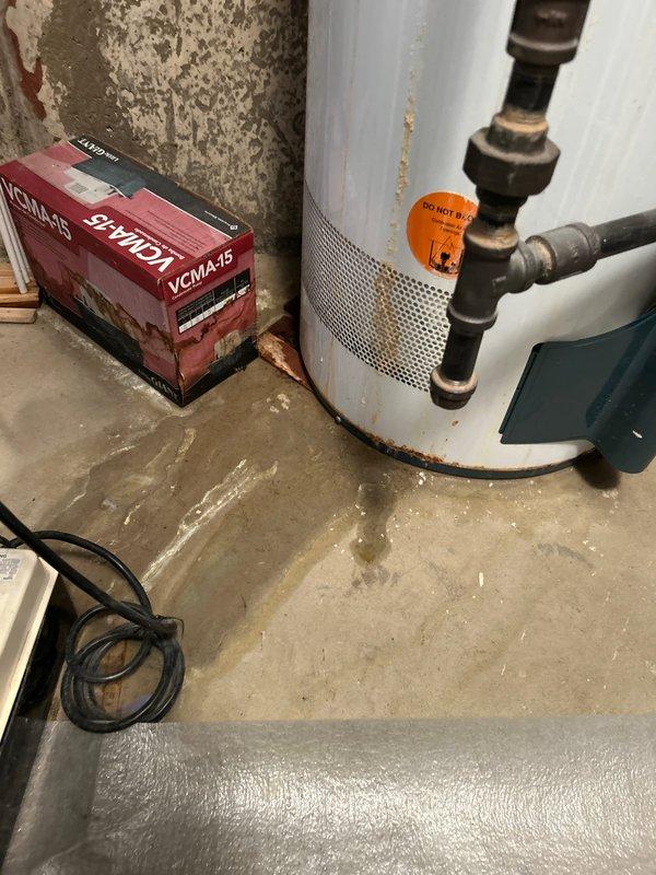 Responded to no hot water complaint at single fixture. Upon arrival, found water supply currently shut off due to previous water line break from last year that resulted in minimal to no hot water delivery. Inspected water heater and associated plumbing system in basement utility area. Documented existing conditions including aged copper piping with significant corrosion and patina, newer PVC drainage components, and water heater with visible age-related wear. Identified mixed plumbing infrastructure combining old and new materials. Photographed installation for service records showing pipe connections, fittings, and overall system configuration to assess cause of inadequate hot water supply following previous line repair.