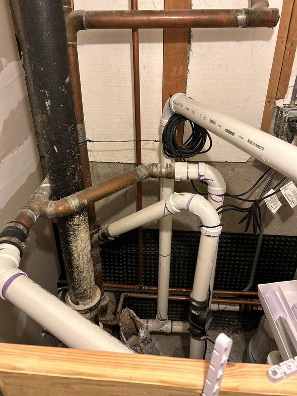 Responded to no hot water complaint at single fixture. Upon arrival, found water supply currently shut off due to previous water line break from last year that resulted in minimal to no hot water delivery. Inspected water heater and associated plumbing system in basement utility area. Documented existing conditions including aged copper piping with significant corrosion and patina, newer PVC drainage components, and water heater with visible age-related wear. Identified mixed plumbing infrastructure combining old and new materials. Photographed installation for service records showing pipe connections, fittings, and overall system configuration to assess cause of inadequate hot water supply following previous line repair.