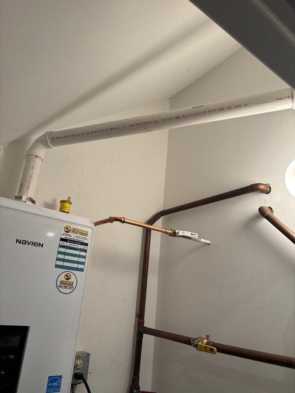 Responded to callback for recurring error code on Navien tankless water heater system. Upon arrival, unit was operating normally with display showing 109°F and no active fault codes present. Inspected installation including wall-mounted unit, PVC venting system, copper supply and return lines, and integrated filtration components. Verified all connections, fittings, and control panel functionality. System appeared to have self-resolved since previous service visit. Documented current operating conditions with photos for warranty records.