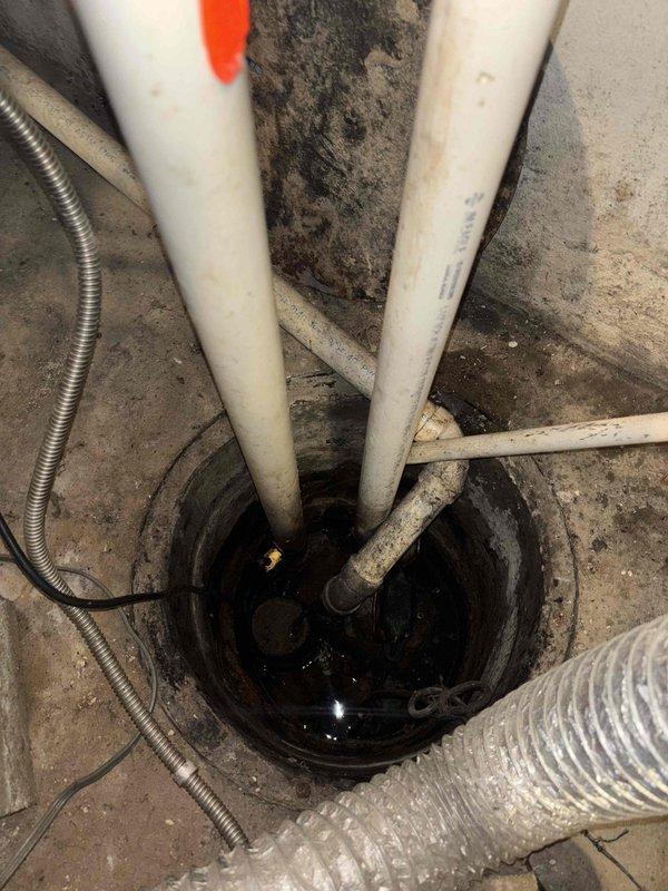 # Sump Pump Replacement Estimate

Responded to service call for malfunctioning sump pump that continuously runs without shutting off. Upon inspection, identified sump pump in basement utility area with failing float switch mechanism causing continuous operation. Assessed existing sump pit configuration with multiple PVC discharge lines and determined complete pump replacement necessary. Documented existing installation including corroded piping connections, aged flexible ductwork in vicinity, and deteriorated concrete floor conditions around pit opening. Provided comprehensive estimate for new sump pump installation with proper float switch assembly and discharge piping upgrades to restore proper automatic operation and prevent potential basement flooding.