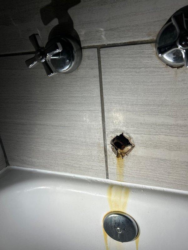 Responded to customer report of low water pressure in bathroom. Upon inspection, discovered deteriorated tub faucet with compromised valve assembly causing restricted water flow and visible mineral staining from wall penetration. Removed existing wall-mounted faucet fixtures with cross-handle controls, addressed water damage behind tile where plumbing connections had been leaking, and installed replacement tub faucet assembly. Restored proper water pressure and flow to bathtub fixture.