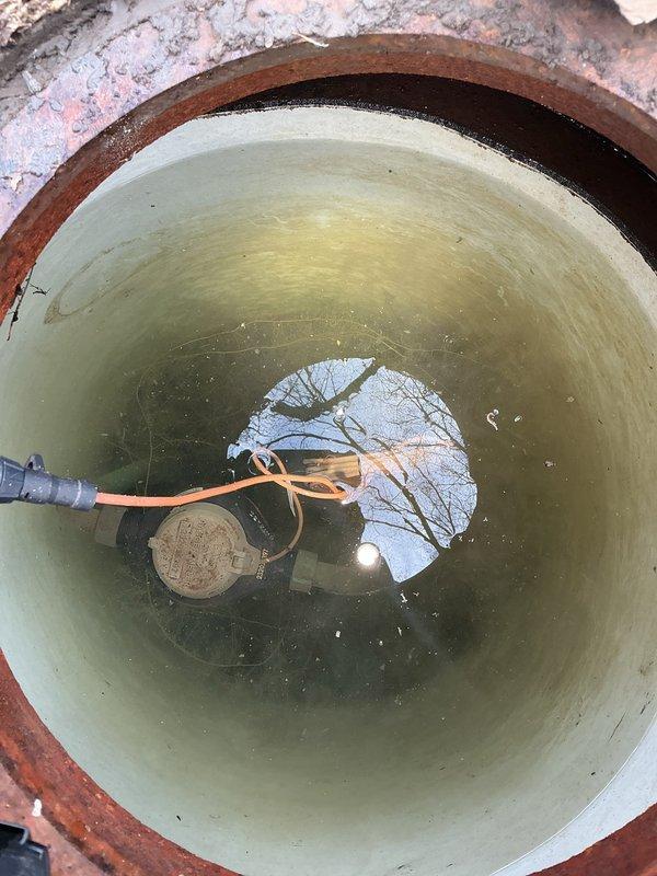 Responded to service call for sewer repair estimate where previous contractor had discontinued work after excavating approximately 4 feet down. Upon arrival, assessed existing excavation site revealing a water-filled trench with exposed sewer line and deteriorated surrounding flooring materials including terracotta tiles. Inspected utility access pit containing submersible pump with standing water and visible reflections indicating proper depth. Documented site conditions including muddy trench with visible debris, exposed white pipe fitting in center of excavation, and rusted metal collar surrounding pit access point. Evaluated scope of remaining work required to complete sewer line repair from current excavation depth, noting existing infrastructure condition and drainage system components. Prepared comprehensive estimate for continuation of sewer repair project based on observed site conditions and required remediation work.