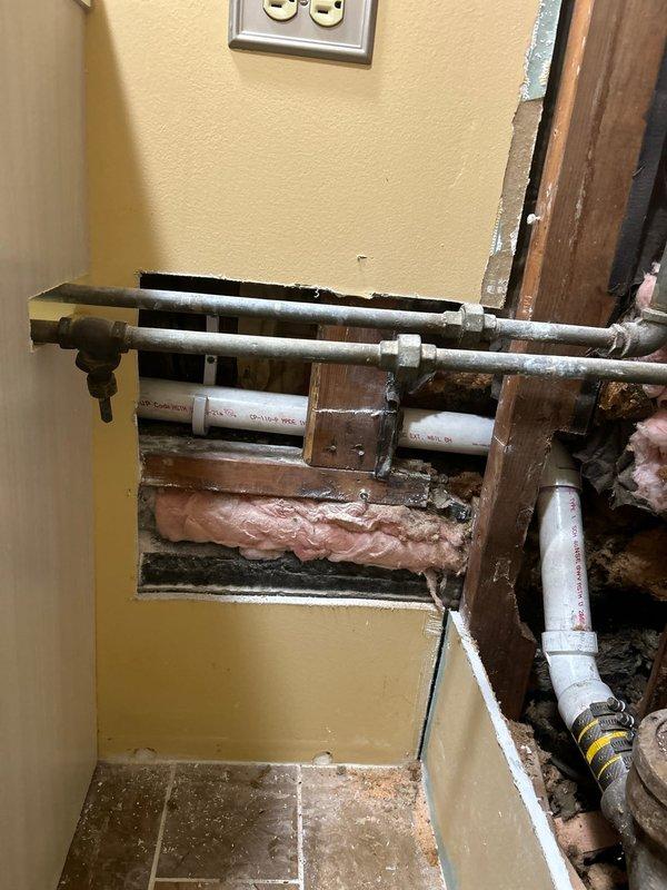 Completed plumbing installation work involving exposed piping systems within interior wall cavity. Installed and configured multiple water supply lines including horizontal metal pipes and vertical PVC drainage pipes, with proper insulation placement between wall framing members. Work included integration of new piping with existing plumbing infrastructure, ensuring proper connections and joint sealing at all coupling points.