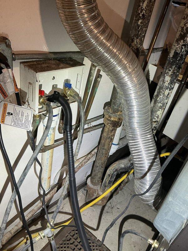 Conducted comprehensive site assessment for plumbing estimate involving collapsed catch basin and deteriorating interior piping systems. Exterior inspection revealed compromised catch basin with exposed cavity, debris accumulation, and structural failure in concrete pad adjacent to HVAC equipment. Interior evaluation documented aging galvanized steel supply lines exhibiting advanced corrosion, surface deterioration, and compromised integrity serving kitchen and laundry areas. Assessed existing brass valve assemblies with flexible connector tubing and identified corroded copper piping with visible patina requiring replacement to prevent future failures and ensure code compliance.