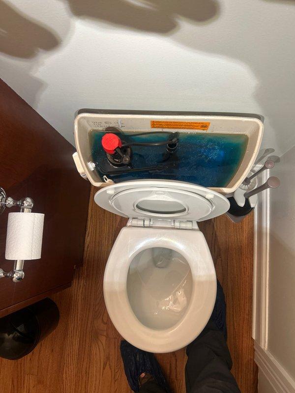 Responded to warranty callback for continuously running toilet that was previously serviced. Upon inspection, observed blue cleaning tablet in tank water and examined flush valve assembly with red float mechanism and black linkage components. Diagnosed issue with internal tank mechanisms causing constant water flow. Adjusted and tested flush valve operation to restore proper function and eliminate running water condition.