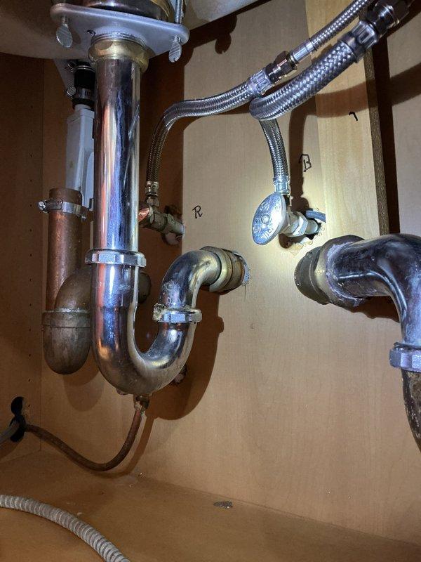 Removed existing garbage disposal unit and disconnected all associated electrical and plumbing connections. Installed new standard P-trap drain assembly with chrome-plated tailpiece to convert sink to conventional drainage configuration. Replaced kitchen faucet with new fixture, connecting hot and cold water supply lines using braided stainless steel flex hoses. Verified all connections for proper seal, tested drain flow and faucet operation, and confirmed no leaks present in supply lines or drain assembly upon completion.