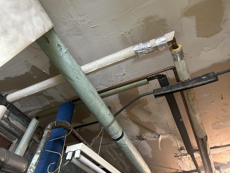 Conducted commercial water heater assessment for upgrading existing 50-gallon unit to 75-gallon capacity. Inspected current gas-fired water heater installation in basement mechanical room, documenting existing plumbing connections, gas line configuration, and venting system. Evaluated overhead piping infrastructure and available space for larger capacity unit replacement.