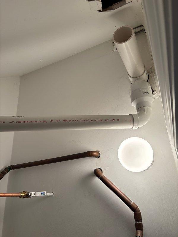 Responded to callback for recurring error code on plumbing system. Inspected utility room mechanical space including white PVC drainage/ventilation piping, copper supply lines with shut-off valves, and wall-mounted venting components. Documented existing pipe configuration and connections at wall and ceiling junctions. Issue requires further diagnosis to resolve persistent error code condition.