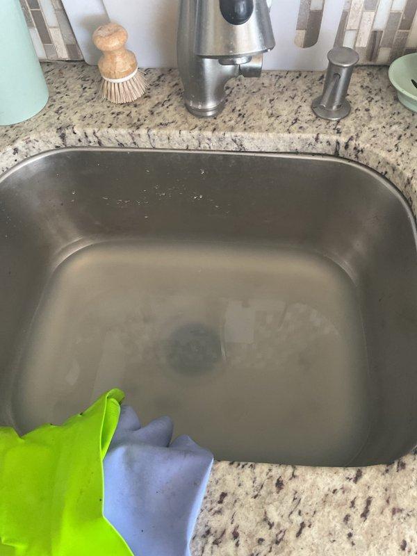 Responded to a clogged kitchen sink with standing water in the basin. Inspected the undermount stainless steel sink and examined the under-sink plumbing assembly, including the P-trap and PVC drain connections. Cleared the blockage to restore proper drainage function.