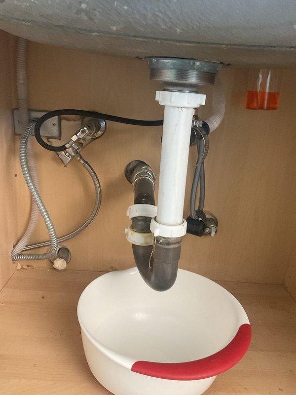 Responded to a clogged kitchen sink with standing water in the basin. Inspected the undermount stainless steel sink and examined the under-sink plumbing assembly, including the P-trap and PVC drain connections. Cleared the blockage to restore proper drainage function.