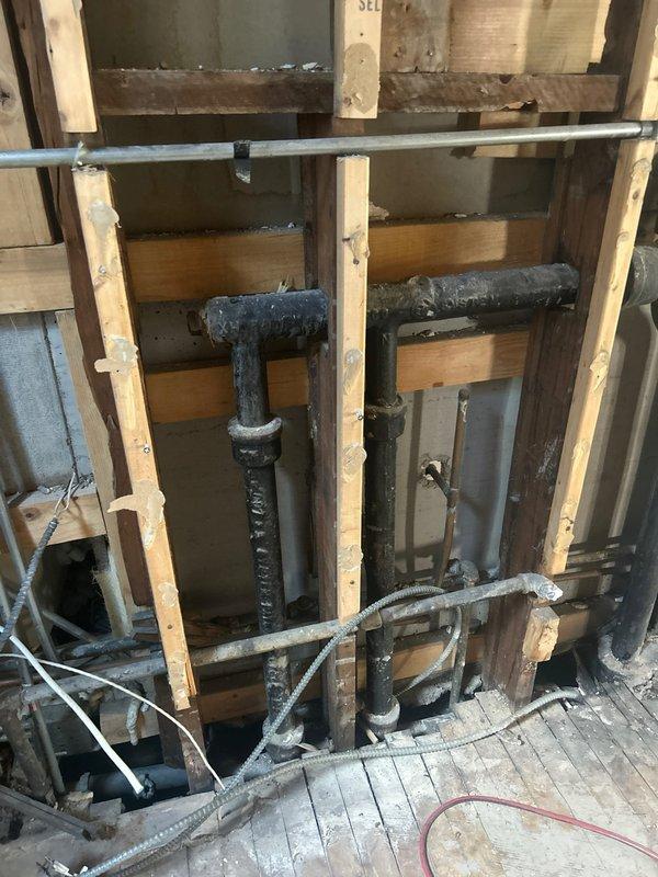 Conducted comprehensive assessment of exposed cast iron drainage piping behind bathroom wall in 102-year-old residence during active renovation. Evaluated condition of vertical and horizontal cast iron stack and branch lines, inspecting for corrosion, deterioration, and structural integrity before wall closure. Documented existing plumbing configuration including pipe routing, joint conditions, and connection points to determine whether replacement was necessary prior to completing wall finish work. Provided professional recommendation regarding pipe serviceability and advised on options for proceeding with renovation based on observed pipe condition.