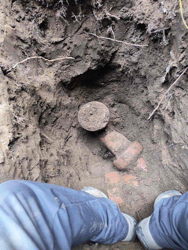 Excavated and exposed deteriorated underground plumbing infrastructure, revealing severely corroded pipe fittings and connections requiring replacement. Installed new white PVC piping system with proper coupling and metal adapter connections, bedding the installation in appropriate sand and gravel material to ensure stable positioning and proper drainage within the trench.