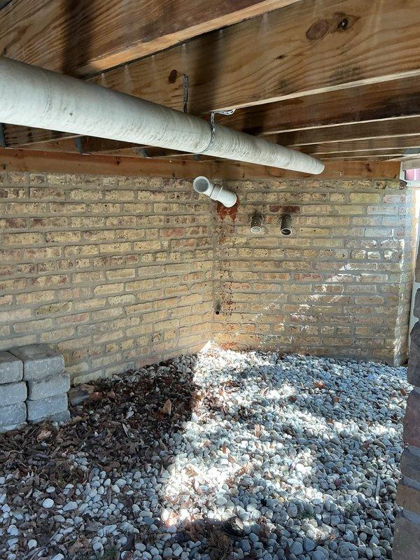 Responded to a tankless water heater leak in a basement closet of a historic residential property. Upon inspection, identified active leaking from the unit that had been occurring for an extended period, evidenced by water damage and mineral deposits in the surrounding area. Performed diagnostic assessment of the tankless water heater system, examining all connections, heat exchanger, pressure relief valve, and internal components. Documented the condition of the unit and installation area with photographic evidence, including views of the gas valve assembly, control board with digital display, electrical connections, and venting configuration. Inspected the mounting against the brick wall and verified all supply and return plumbing connections. Assessed the crawl space environment and drainage conditions around the unit location. Provided recommendations for repair or replacement based on the age and condition of the equipment and extent of the leak.