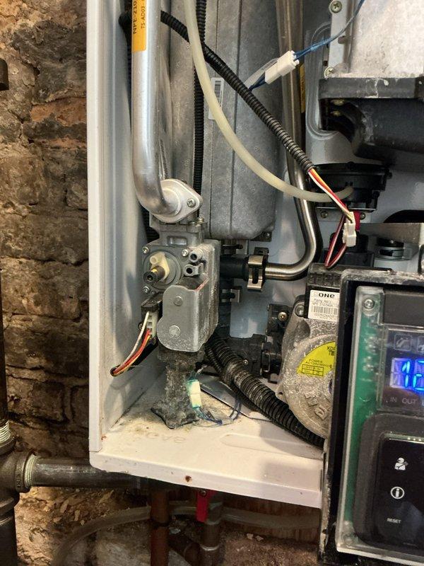 Responded to a tankless water heater leak in a basement closet of a historic residential property. Upon inspection, identified active leaking from the unit that had been occurring for an extended period, evidenced by water damage and mineral deposits in the surrounding area. Performed diagnostic assessment of the tankless water heater system, examining all connections, heat exchanger, pressure relief valve, and internal components. Documented the condition of the unit and installation area with photographic evidence, including views of the gas valve assembly, control board with digital display, electrical connections, and venting configuration. Inspected the mounting against the brick wall and verified all supply and return plumbing connections. Assessed the crawl space environment and drainage conditions around the unit location. Provided recommendations for repair or replacement based on the age and condition of the equipment and extent of the leak.