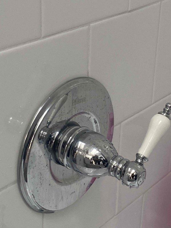 Responded to low water pressure complaint in second-floor bathroom of 20-year-old residence. Upon inspection, identified deteriorated shower valve cartridge causing restricted flow. Removed decorative trim plate and escutcheon to access valve assembly, revealing corrosion and mineral buildup on valve stem and internal components. Replaced faulty cartridge, cleaned mounting area, and reinstalled handle assembly. Tested water pressure and temperature control to confirm proper operation and full flow restoration.