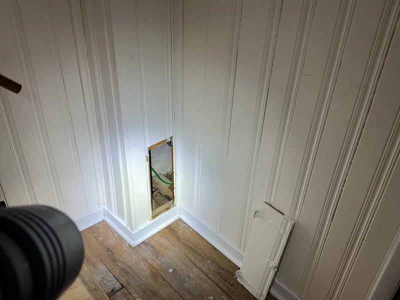Responded to estimate request for suspected broken sewer line at bottom of toilet stack. Created access opening in white paneled wall to expose plumbing system and assess condition of drainage pipes. Investigation revealed gray PVC drain stack and associated plumbing components requiring evaluation for potential repair or replacement of compromised sewer line section.