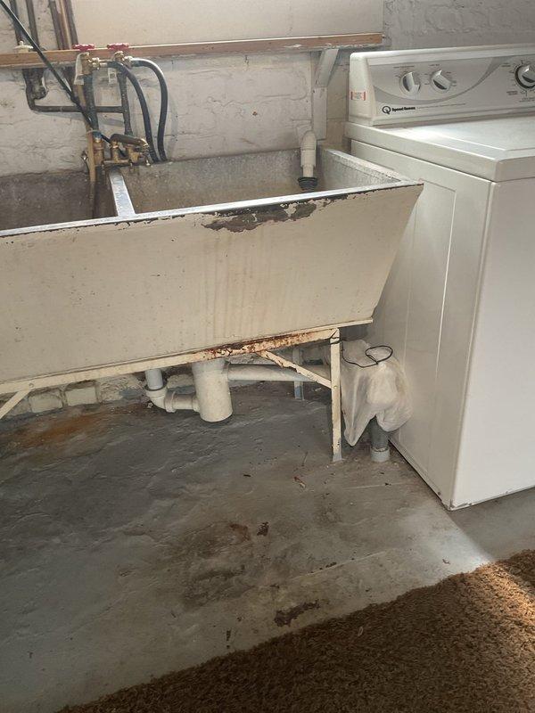 Responded to service call for sewer scope estimate at residential property. Upon arrival, inspected basement utility area to assess plumbing system and identify access points for camera inspection. Observed aging plumbing infrastructure including galvanized piping with visible corrosion, utility sink with deteriorated base framing, and floor drain connections with PVC drainage pipes. Documented existing conditions including water staining on concrete floor indicating potential drainage issues, compromised sink support structure, and corroded water meter assembly. Photographed plumbing configuration and areas of concern to provide comprehensive estimate for sewer scope inspection and recommended repairs based on visual assessment of accessible plumbing components.