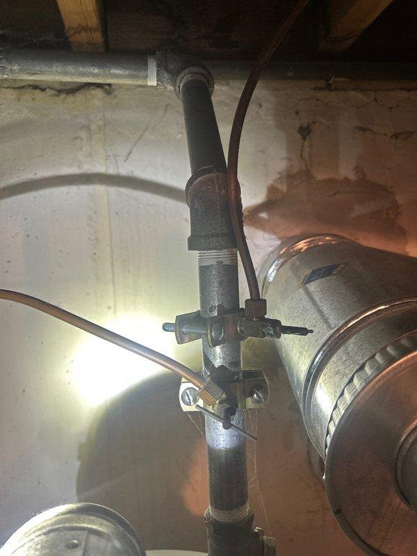 Conducted on-site assessment of existing 50-gallon A.O. Smith water heater located in basement of 60-year-old residential property. Inspected current plumbing configuration, including vertical pipe assembly with multiple valve connections and copper branch lines mounted against foundation wall. Evaluated existing installation beneath floor joists, noting galvanized steel piping with threaded fittings and copper distribution components. Photographed current water heater setup and surrounding plumbing infrastructure to document existing conditions. Prepared estimate for water heater upgrade, accounting for age of home and existing plumbing connections that will require integration with new unit.