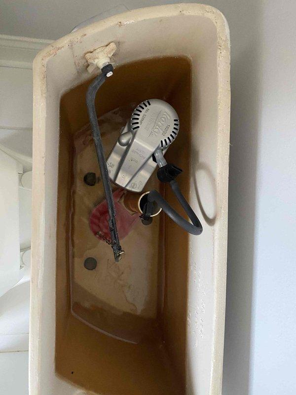 Responded to water leak complaint with visible ceiling damage and toilet flushing issues. Inspected toilet tank mechanisms revealing significant mineral buildup, discolored water, and deteriorated internal components including corroded fill valve assembly and compromised flapper valve. Investigated ceiling moisture patterns to identify leak source and assessed potential connection between indoor plumbing fixtures and reported outdoor patio water intrusion.