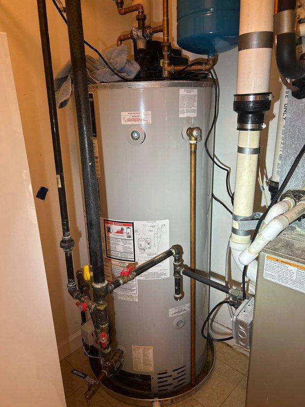 Responded to service call for water leak originating from copper supply lines above water heater. Upon inspection, identified active leak at copper piping connections near top of water heater unit where brass fittings interface with copper supply lines. Examined complete plumbing system in utility room including water heater installation, pressure tank, shut-off valves, and associated copper, PVC, and black iron piping. Documented conditions of all plumbing components, connections, and potential leak sources throughout the system. Inspected exterior access areas and perimeter of structure for additional plumbing concerns as requested.