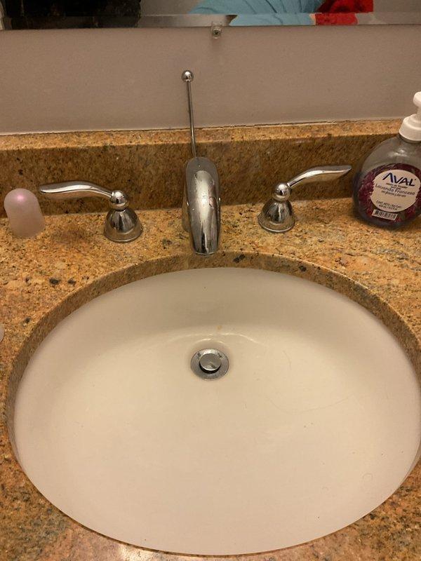 Responded to service call for malfunctioning bathroom sink stopper and drainage issue. Upon inspection, assessed the pop-up drain assembly beneath the undermount porcelain sink and verified the P-trap configuration and drain connections. Serviced the chrome pop-up stopper mechanism to restore proper operation, ensuring the sink now drains efficiently and the stopper functions as intended.