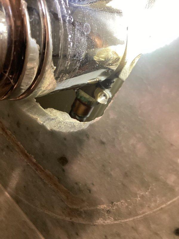 Investigated water damage on ceiling below shower and documented conditions. Inspection revealed significant water staining and discoloration on ceiling surface with irregular patterns indicating infiltration from above, along with moisture accumulation on copper piping components in the affected area. Photographed damaged areas and mechanical components for warranty documentation and further assessment of leak source.