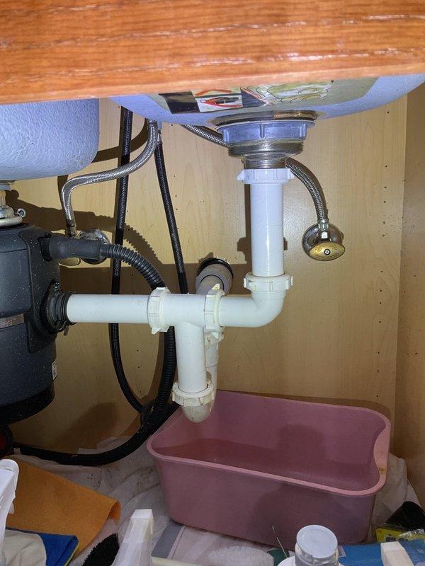 Responded to priority service call for leaking kitchen faucet. Upon arrival, performed comprehensive assessment of modern stainless steel pull-down spray faucet installed on double-bowl undermount sink with black granite countertop. Inspected faucet assembly, spray head mechanism, and mounting hardware from above-counter position. Examined under-sink plumbing connections, supply lines, and drain assembly including P-trap configuration and garbage disposal unit connections. Documented existing conditions with photographs showing faucet system, sink installation, and cabinet plumbing arrangement. Provided technical evaluation and recommendations regarding repair versus replacement options based on observed leak source and overall fixture condition.