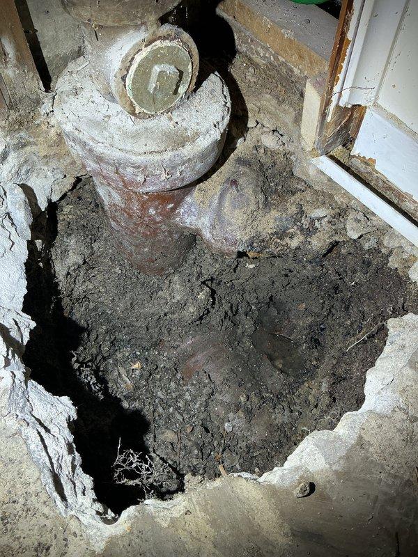 Completed residential drain and sewer estimate for deteriorated basement plumbing system. Assessment revealed aged vertical drainage pipes with significant discoloration and buildup, compromised floor surfaces with extensive moisture damage around drain fixture, and exposed utilities requiring attention. Documented existing conditions through photography showing corroded pipe infrastructure, degraded concrete flooring with substrate exposure, and unfinished utility space with visible water intrusion issues requiring comprehensive drain and sewer system evaluation for repair recommendations.