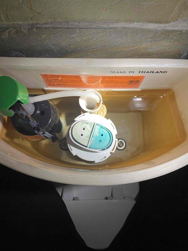 Inspected toilet tank and flush mechanism due to water discoloration concerns. Found brownish-tinted water in tank and identified dual-flush valve system requiring attention. Documented existing tank components including fill valve assembly and flush mechanism for repair recommendation.