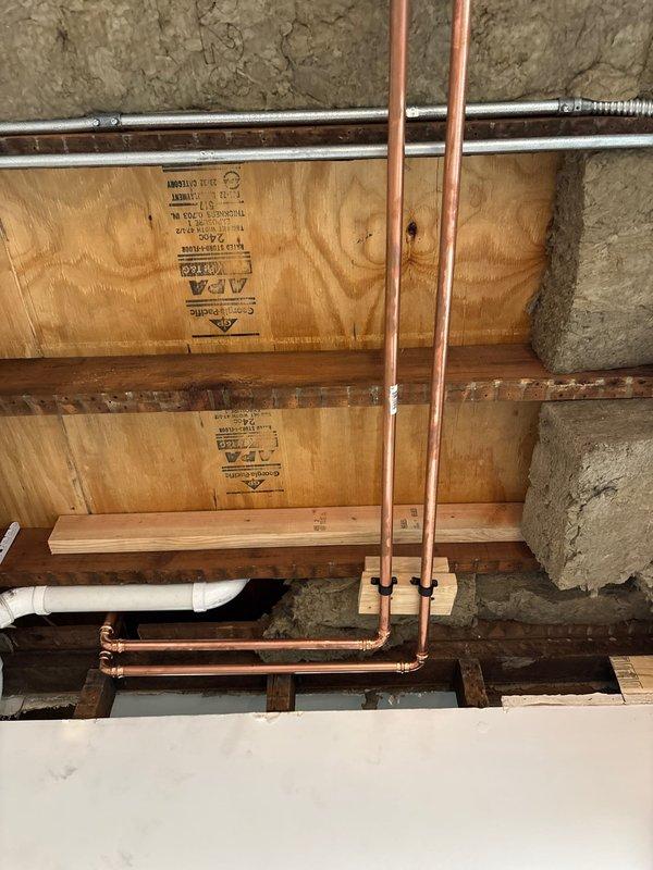 Completed attic portion of plumbing repair involving copper pipe installation and rerouting through floor joists and wall cavities. Accessed work areas through ceiling and wall openings, installed new copper supply lines with proper support blocking, and integrated connections with existing PVC drainage system. Customer requested to postpone laundry room portion of project until summer season, with first phase now complete and ready for closure.