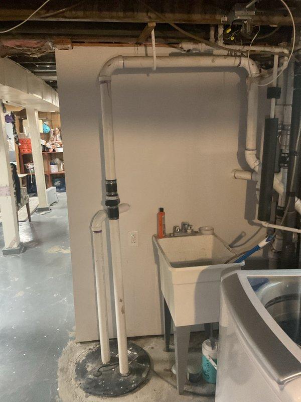 Conducted plumbing assessment of basement ejector pump system and evaluated discharge piping options for connection to sanitary sewer line. Documented existing PVC drainage infrastructure, water meter assembly, utility sink installation, and current pump configuration to provide customer with multiple solutions for proper ejector pump discharge routing.