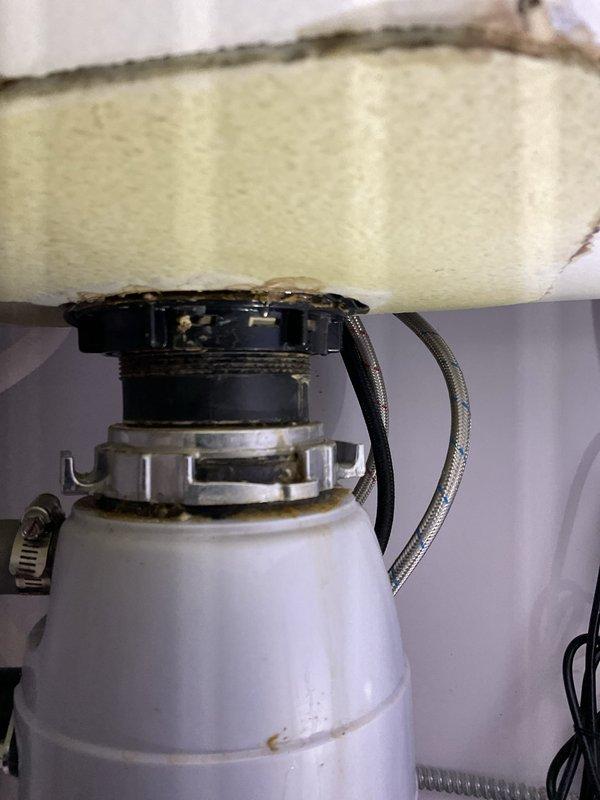 Responded to service call for leaking connection between kitchen sink and garbage disposal unit. Upon inspection, identified compromised seal at disposal mounting flange where unit connects to sink drain. Disassembled mounting assembly, cleaned mating surfaces, replaced worn rubber gasket and fiber gasket at flange connection, and reinstalled disposal unit with proper torque on mounting ring. Tested system under full water flow to verify leak was resolved and all connections remained dry.