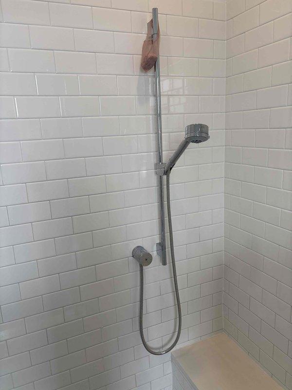 Successfully installed new shower head and replaced flexible metal hose on euro-bar slide system. Replaced worn set screws on the handheld shower head holder to ensure secure mounting and proper adjustment along the vertical slide bar. All chrome fixtures were properly secured and tested for functionality, with water flow and spray patterns verified to be operating correctly.
