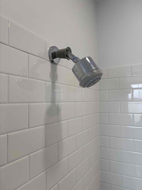 Successfully installed new shower head and replaced flexible metal hose on euro-bar slide system. Replaced worn set screws on the handheld shower head holder to ensure secure mounting and proper adjustment along the vertical slide bar. All chrome fixtures were properly secured and tested for functionality, with water flow and spray patterns verified to be operating correctly.