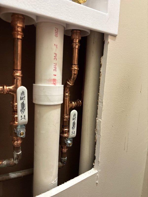 Completed laundry box replacement in utility closet. Removed existing drywall to access plumbing connections behind wall cavity. Installed new laundry box assembly with copper supply lines and PVC drain connections. Supply piping includes hot and cold water connections with proper shutoff valves. Drain system features 2-inch PVC Type 1 pipe conforming to ASTM standards. All connections properly secured with appropriate fittings and joints. Wall openings cut to accommodate new plumbing configuration and provide access to connections. Floor drain present in tiled utility space. All plumbing components installed per code requirements and tested for proper operation.