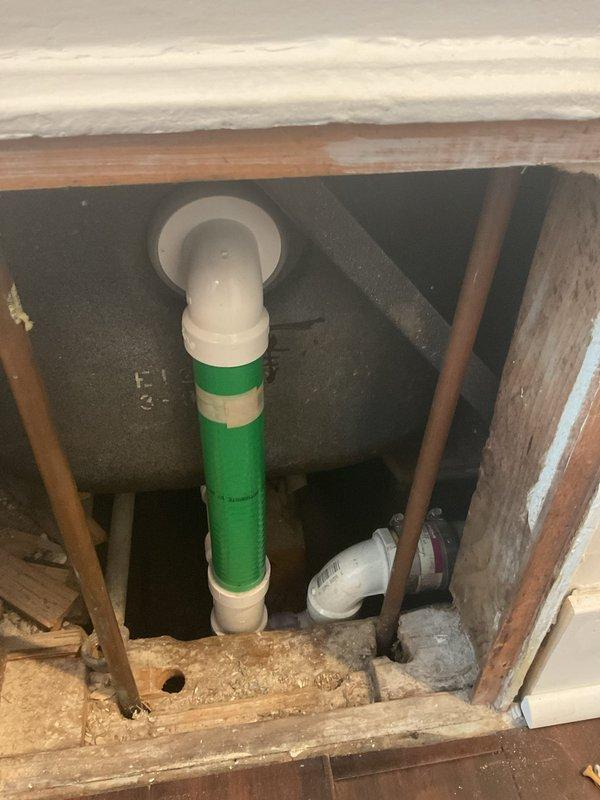 Responded to service call for bathtub draining extremely slow. Upon inspection, discovered significant accumulation of debris, dirt, and grime around the drain and basin area. Accessed plumbing system beneath the fixture, cleared obstruction from drainage line, and verified proper flow through the green PVC vertical stack and connected white PVC piping. Drainage restored to normal function and system tested successfully.
