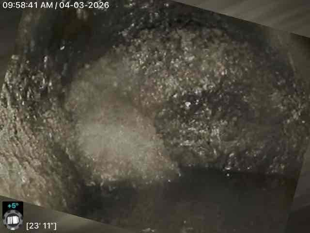 Performed video camera inspection of residential sewer line extending approximately 23 feet into the system. Documentation revealed significant accumulation of debris, mineral deposits, and particulate buildup coating the interior pipe walls throughout the inspected section. Captured detailed photographic evidence showing heavy scaling and material accumulation that could restrict flow capacity and require cleaning or further remediation.
