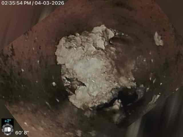 Performed video camera inspection of sewer line beginning at exterior concrete entrance steps. Camera was inserted and advanced 60 feet 8 inches into the pipe system. Inspection revealed significant mineral deposit accumulation and sediment buildup within the line, with crusty white calcification covering substantial portions of the pipe bottom. Documented findings with photographic evidence showing the extent of buildup and current pipe condition for maintenance planning and future service recommendations.
