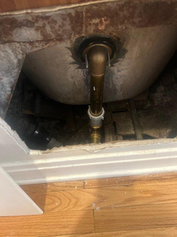 Performed comprehensive leak assessment in 1920s three-flat building to identify source of water stains on ceiling and wall between units. Conducted visual inspection of bathroom floor cavity in upper unit, revealing extensive water damage and deterioration around toilet drain assembly with brass piping and visible staining indicating prolonged moisture exposure. Documented compromised flooring materials and structural elements within access area, as well as modern bathroom fixtures in affected unit including vessel sink with active water flow testing. Discussed findings with property occupants and recommended exploratory work requiring access through upper unit flooring to properly isolate leak source and provide accurate scope of work for permanent repairs.