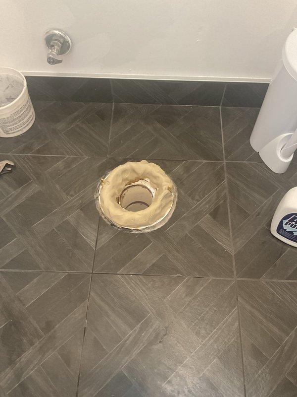 Responded to callback for persistent sewer odor in bathroom that customer had been monitoring since previous visit. Upon inspection, removed toilet tank lid and examined flush mechanism and internal components. Identified heavily stained and deteriorated toilet flange with significant buildup and discoloration indicating improper seal at floor connection. Assessed wax ring seal integrity and flange condition as source of sewer gas escape into bathroom space.