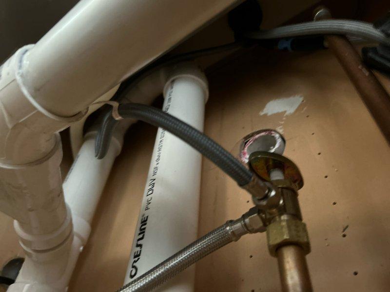 Cored through the base of the kitchen cabinet and installed 2" PVC drain pipework with cleanout access. Ran drain lines into the basement and connected to existing galvanized drain and vent system using proper fastening hangers and support brackets. Installed dedicated P-trap for dishwasher discharge line and separate P-trap assembly for right side basin. Connected garbage disposal unit with corrugated flexible discharge hose to drain system. Installed water supply lines using braided stainless steel flex lines connected to chrome shutoff valves and copper supply piping. Mounted water filtration device horizontally within cabinet space and integrated into supply system. All connections tested and verified for proper drainage and no leaks.