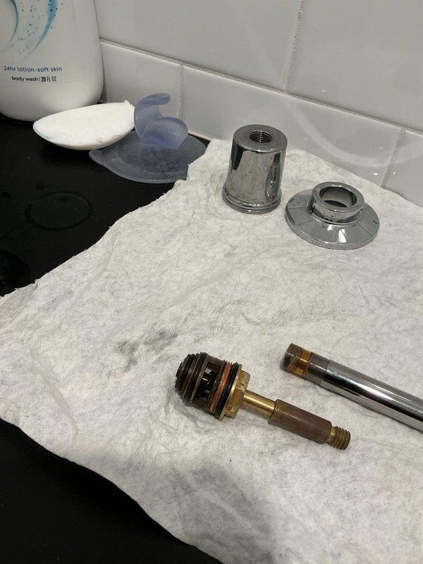 Completed shower valve repair by disassembling and replacing worn brass valve stem assembly with degraded o-rings and seals. Removed corroded components, cleaned threaded connections, installed new chrome trim pieces and escutcheon plate, and tested system for proper water flow and temperature control.