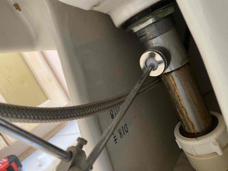 Responded to service call for leaking bidet fixture. Upon inspection, identified leak originating from supply line connection beneath the bidet. Tightened braided flexible supply line connection at the threaded fitting to eliminate water seepage. Verified all chrome-plated faucet components and pop-up drain assembly were functioning properly with no additional leaks detected. Documented fixture condition with photos showing three-handle bidet configuration and underlying plumbing connections for service records.