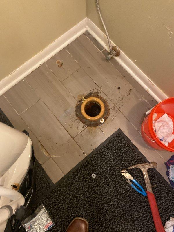 Responded to a toilet leak caused by a severely corroded closet flange in a 65-year-old home. Removed the existing toilet to access the damaged flange, which showed significant rust and corrosion around the mounting area with visible deterioration on the surrounding tile surface. Replaced the corroded brass flange with a new unit, ensuring proper seal and secure mounting to prevent future leaks. Reinstalled the toilet with new wax ring and hardware, tested for leaks, and verified proper operation of the fixture with safety rail attachment.