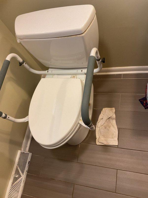 Responded to a toilet leak caused by a severely corroded closet flange in a 65-year-old home. Removed the existing toilet to access the damaged flange, which showed significant rust and corrosion around the mounting area with visible deterioration on the surrounding tile surface. Replaced the corroded brass flange with a new unit, ensuring proper seal and secure mounting to prevent future leaks. Reinstalled the toilet with new wax ring and hardware, tested for leaks, and verified proper operation of the fixture with safety rail attachment.