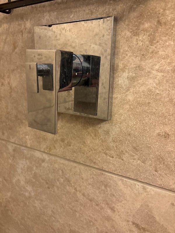 Responded to no hot water issue in shower at older residential property. Upon inspection, diagnosed problem with water heater supply or mixing valve affecting hot water delivery to bathroom fixtures. Examined shower control assembly with chrome fixtures and diverter valve mounted on travertine tile wall. Traced plumbing system to main water meter location with aged copper supply lines showing oxidation. Tested water temperature at multiple fixtures to isolate issue. Restored full hot water function to shower by addressing supply line restriction and verifying proper operation of mixing valve. System now delivering appropriate hot water temperature and pressure to shower fixture.