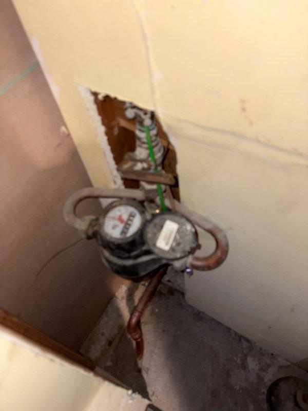 Responded to no hot water issue in shower at older residential property. Upon inspection, diagnosed problem with water heater supply or mixing valve affecting hot water delivery to bathroom fixtures. Examined shower control assembly with chrome fixtures and diverter valve mounted on travertine tile wall. Traced plumbing system to main water meter location with aged copper supply lines showing oxidation. Tested water temperature at multiple fixtures to isolate issue. Restored full hot water function to shower by addressing supply line restriction and verifying proper operation of mixing valve. System now delivering appropriate hot water temperature and pressure to shower fixture.