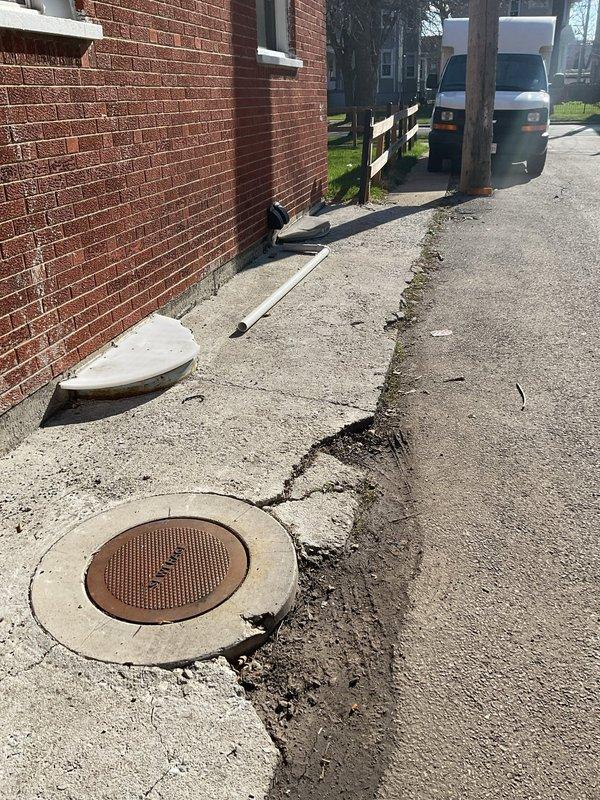 Responded to customer request for catch basin cleaning due to debris accumulation and backup issues. Upon arrival, found deteriorated concrete catch basin with heavily corroded metal cover displaced from opening. Extensive debris and sediment observed at bottom of basin. Removed rusted cover and performed thorough cleaning of catch basin to eliminate blockage and restore proper drainage function. Surrounding concrete surface showed significant weathering with visible cracks radiating from opening. Successfully cleared all debris and backup, restoring full operational capacity to the catch basin system.