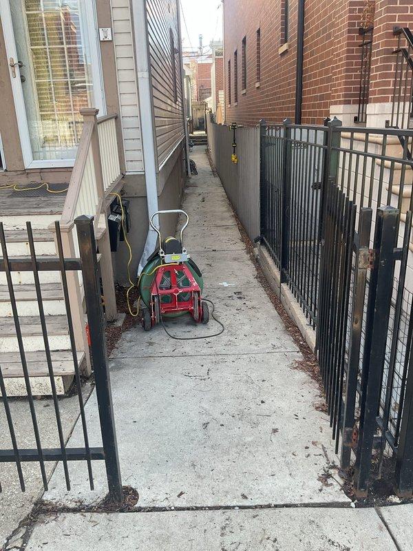 Responded to flooded drain concern located under deck area. Accessed service alleyway between residential structures to assess drainage system backup. Deployed equipment through narrow passageway to investigate standing water accumulation in subsurface drain line. Performed diagnostic evaluation of exterior drainage infrastructure and identified source of flooding condition.